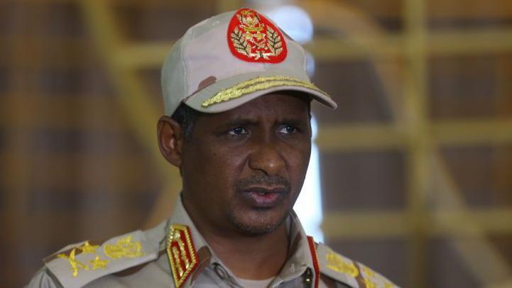 Mohamed Hamdan Dagalo wearing a beige military cap with a round red logo.