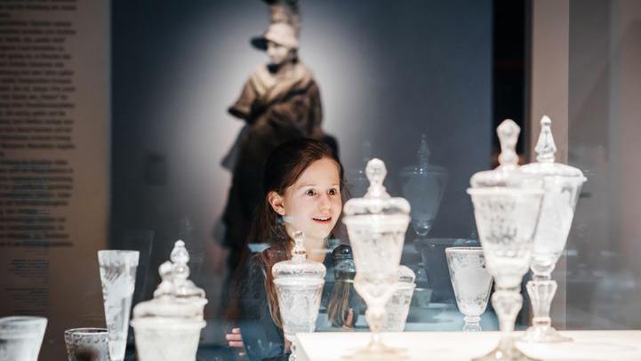 girl looking at old glassware in museum