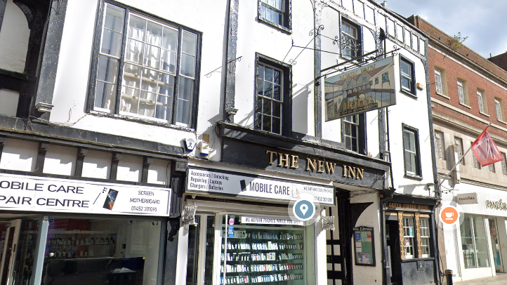 A black and white Tudor-style building sitting above a "mobile care" shop.