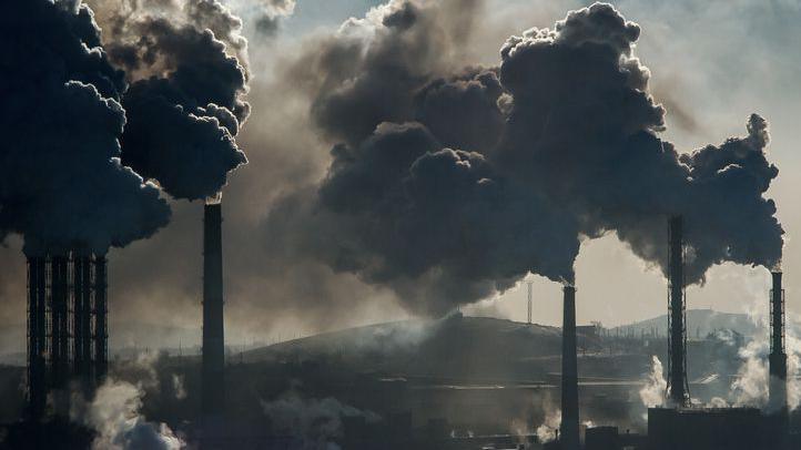Chimneys at a power plant with lots of smoke in the air.