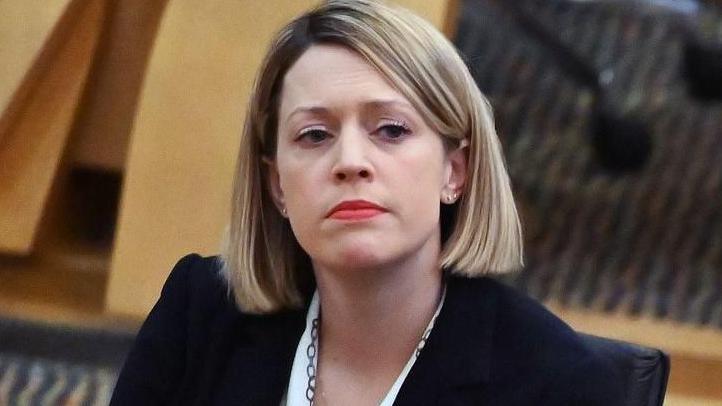 Education Secretary Jenny Gilruth in parliament. She has a blonde bob and is wearing a white shirt and a black jacket 