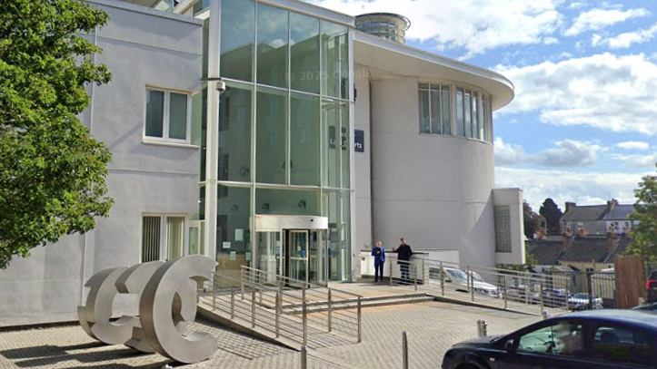 A light-coloured court building with a large floor to ceiling glass entrance way.