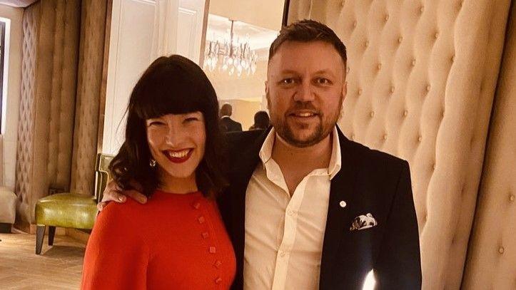 Rachel Prendergast wearing a red dress and Richard Prendergast wearing a suit and white shirt