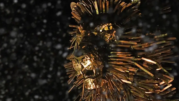 A bronze statue of Aslan The Lion looks out over a square