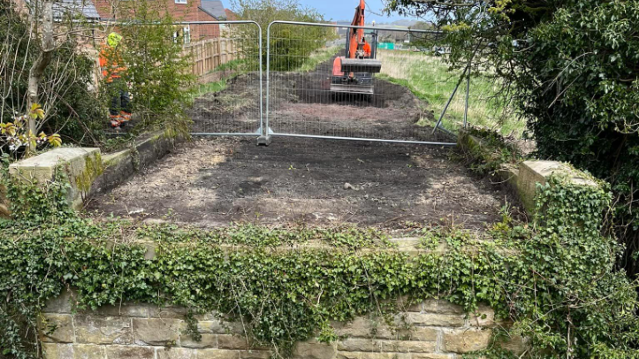 A digger at work next to a gap where a bridge once stood