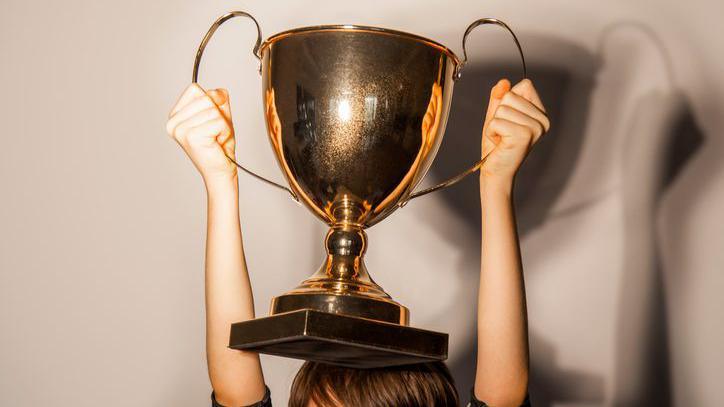 Boy holding a gold trophy above his head.