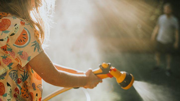 A child spraying a garden hose. 