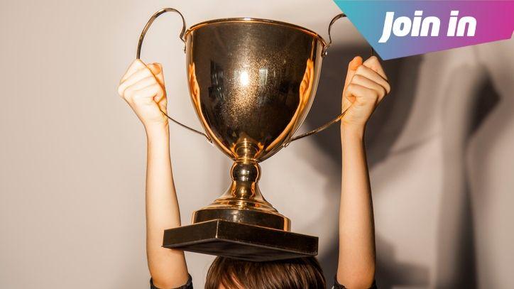A boy holding a gold trophy above his head.