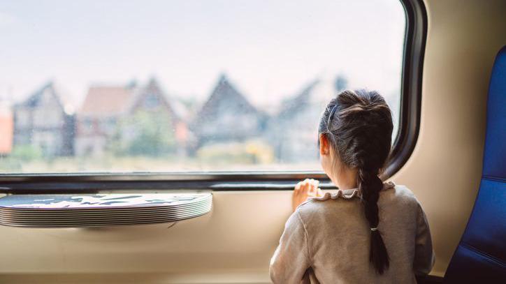 A girl sitting on a train looking out of the window.