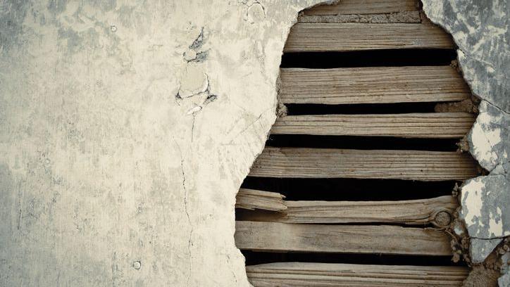 Close up of lath and plaster showing strips of wood behind broken plaster