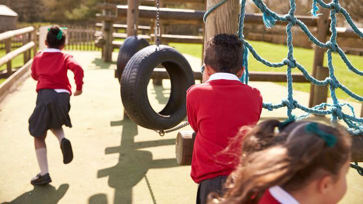 Schoolchildren playing outside in a playground.