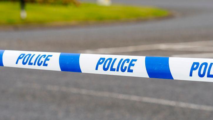 A stock image of a police cordon tape line on a road.