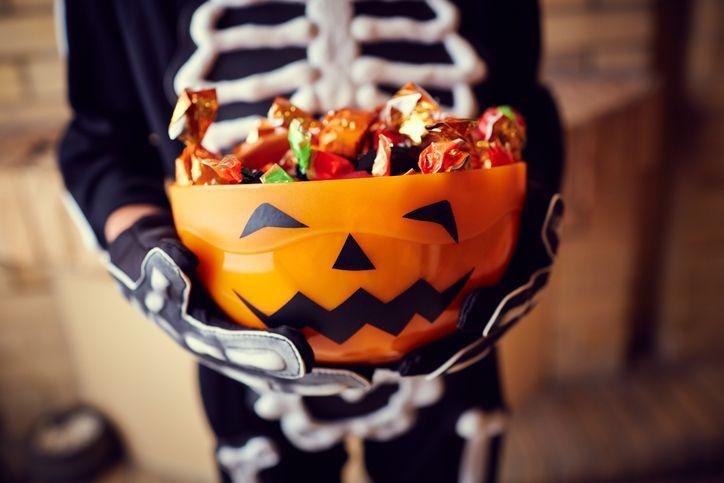 A child holding a pumpkin-decorated bowl full of chocolates