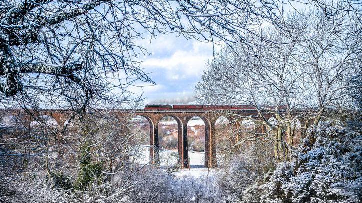 Photo of a train crossing a bridge in winter near Inverness with snow on the ground.