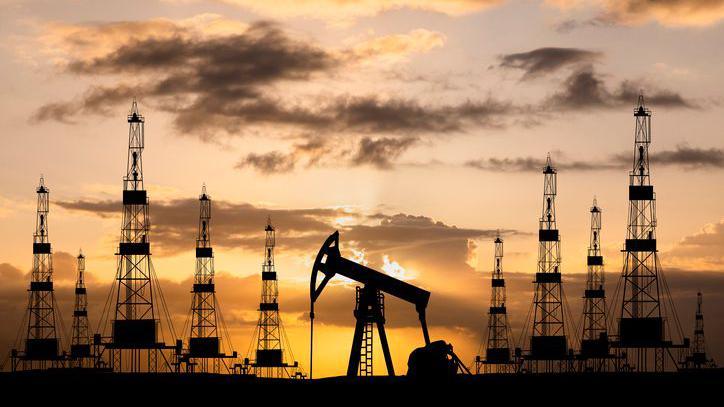 Oil field with rigs and pumps at sunset