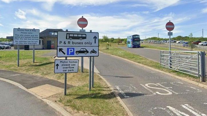 The entrance to the park and ride site. There is a sign indicating only park and ride buses may enter, with a different sign indicating where the public can park.
