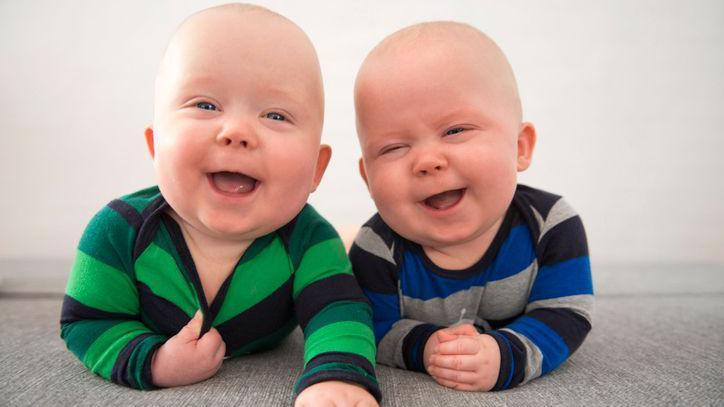 Two identical twins laughing.