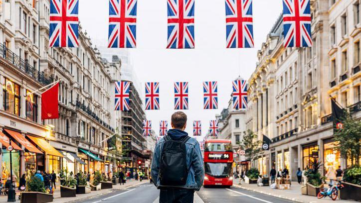 A man standing in the middle of Oxford Street with union jack flags hanging above