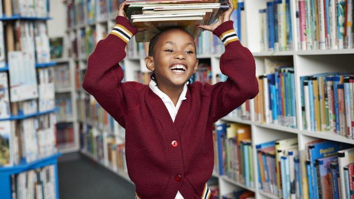 child with a stack of books on her head