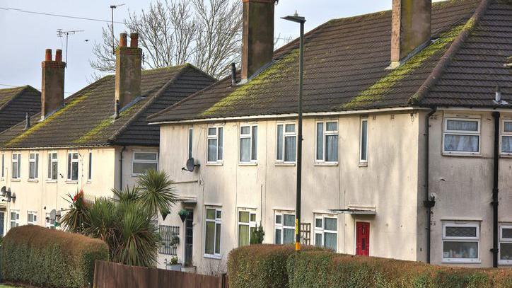 Houses in West Heath, on the the southern edge of Birmingham. The buildings have white walls, roofs with moss on them and chimneys.