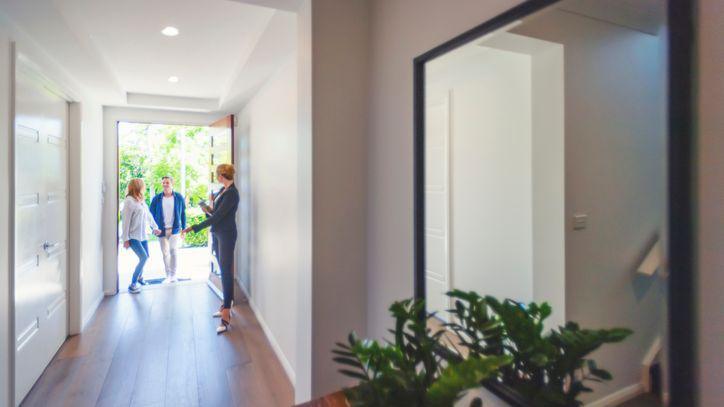 An agent showing a man and women into an open house 