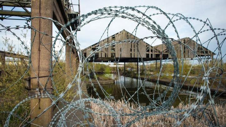 A view of a derelict site, taken in 2022, near the Wolverhampton Steel Terminal  at Chillington Wharf in Wolverhampton. There is a structure in poor repair and barbed wire.