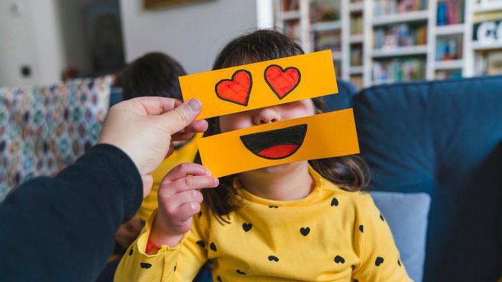 girl holding up emoji signs on paper