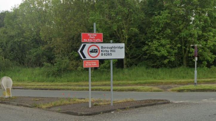 A white road sign reading Bouroughbridge/Kirby Hill