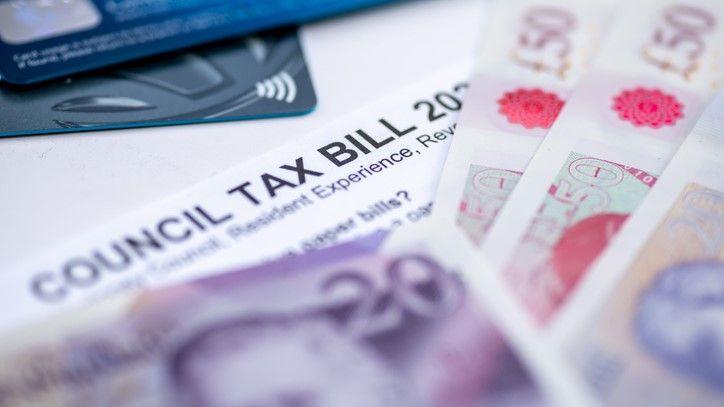 Fifty and twenty pound notes, scattered over a council tax bill. There are credit cards in the background.
