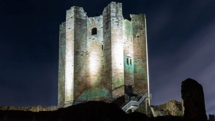 A white stone castle keep lit up at night