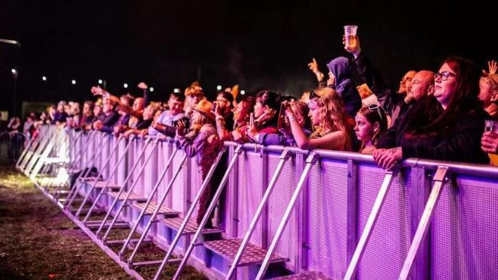 A crowd of people watching an act at a festival 