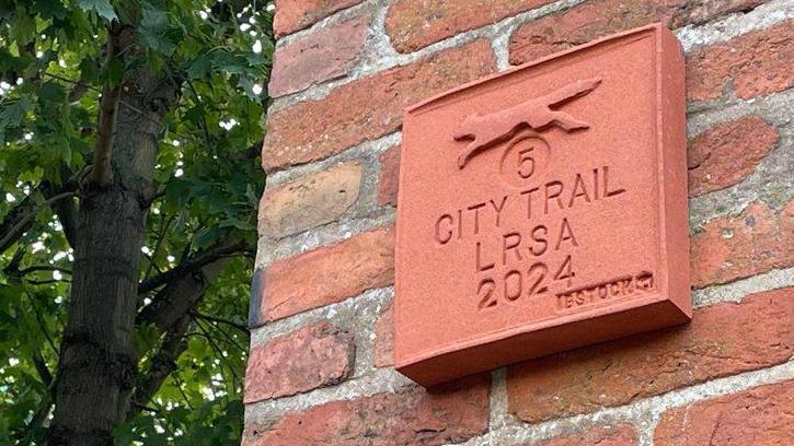 The terracotta plaque is made of red local brick and has Ibstock stamped into the corner. It has a number 5 on it, a fox, and city trail LRSA 2024.  