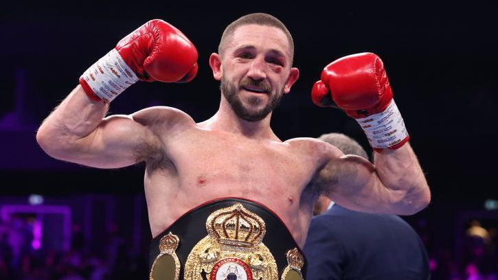 Jazza Dickens is wearing red boxing gloves and holding up his fists