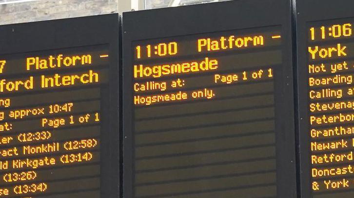 A train announcement board displaying information about a fictional departure to Hogsmeade station 