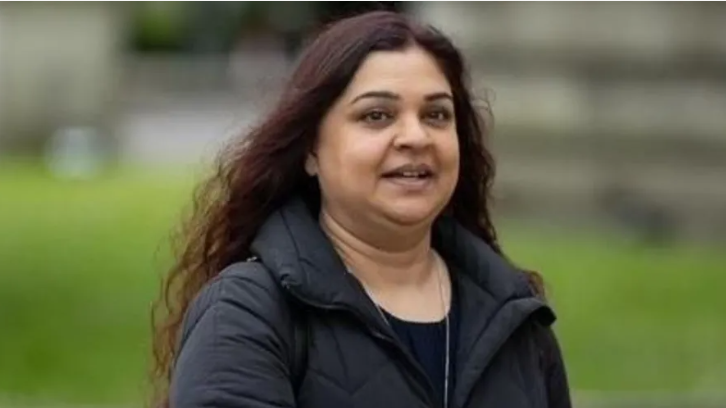 Tanya Nasir wearing a black top and coat, mouth open looking off to side