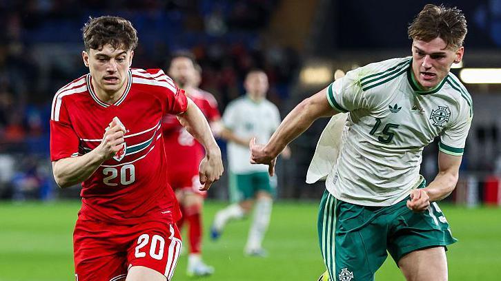 Dan James of Wales and Justin Devenny of Northern Ireland chase the ball during a friendly in Cardiff in March 2026