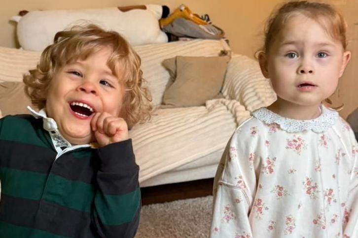 Harry on the left grinning for the camera wearing a green and black striped jumper with Harley on the right with a white jumper with pink flowers on.