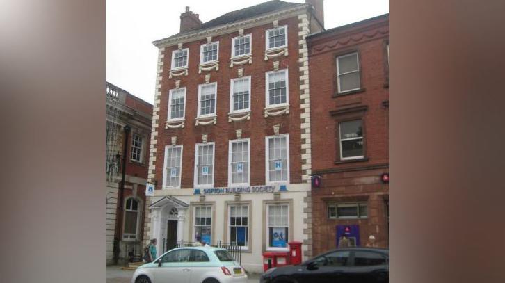 A tall, narrow building with a Georgian appearance. A sign on the front reads "SKIPTON BUILDING SOCIETY".