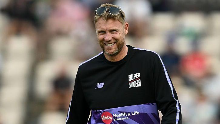 Andrew Flintoff smiling while wearing a Northern Superchargers shirt and a pair of sunglasses on top of his head.