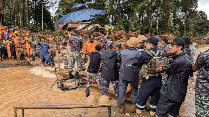 Rescue teams use ropes to cross a broken bridge and reach survivors in Wayanad