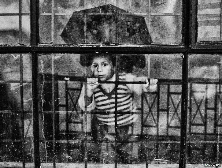 A boy looks from the glass door of the gate of the relief camp in Joshimath.