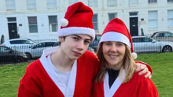 Stefan Kluibenschadl and his mum Emma Kluibenschadl both dressed in Santa outfits and hugging
