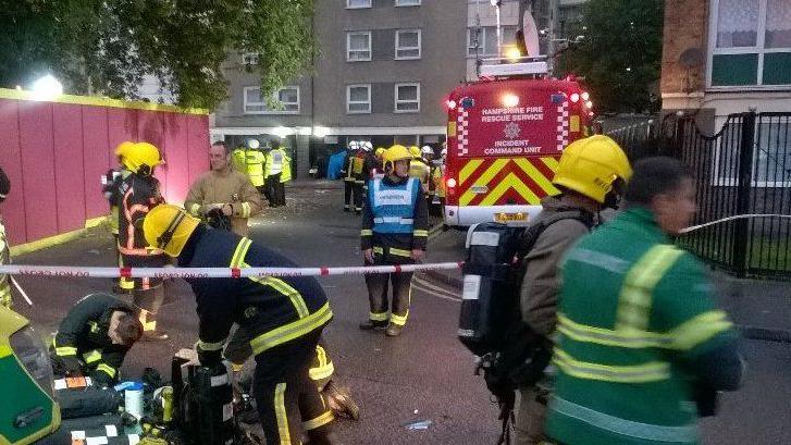 More than a dozen police, fire and ambulance workers are pictured outside Handsworth House, a Portsmouth tower block.