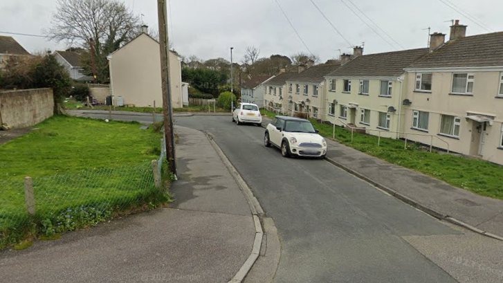 A street view of two cars parked up on a pavement, on a side street in Truro.