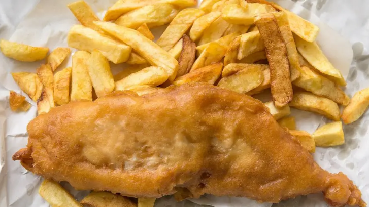 A stock image of fish and chips on white paper.