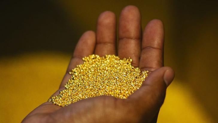 A worker holds a handful of gold bullion granules during manufacture at a plant in Germiston, South Africa, on 16 August 2017