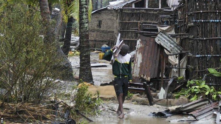 A man collects some wood on a flooded street