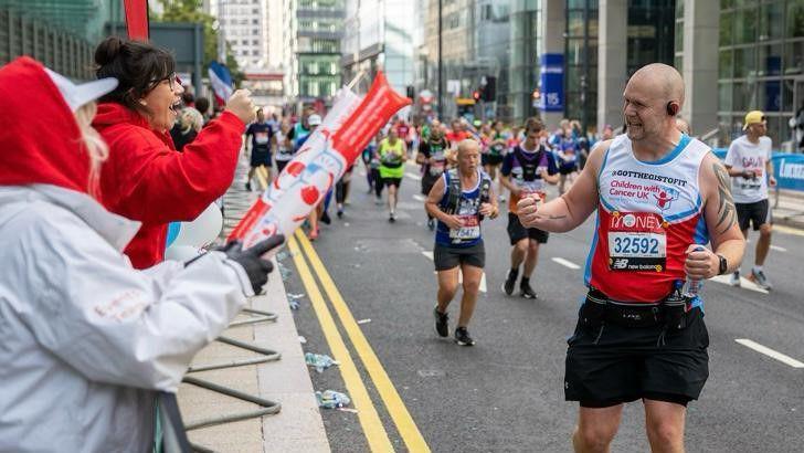 Chris Johnson in the London Marathon. He is clenching his fist in acknowledgement at a supporter who is cheering him on.