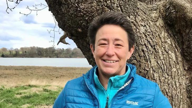 Adria Pittock in a blue fleece and blue jacket standing outside in front of a tree