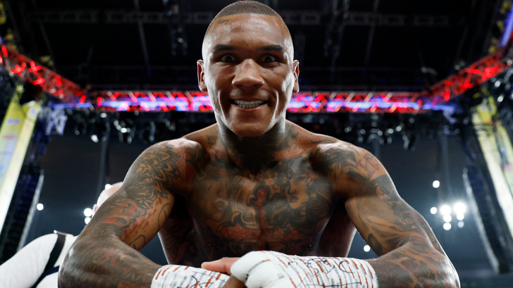 Conor Benn leans over the ropes smiling